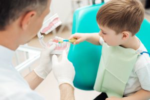 歯医者が子どもに歯磨きを押している