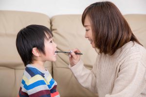 お母さんに仕上げ磨きをしてもらう男の子