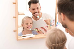 鏡の前で歯磨きをしている親子