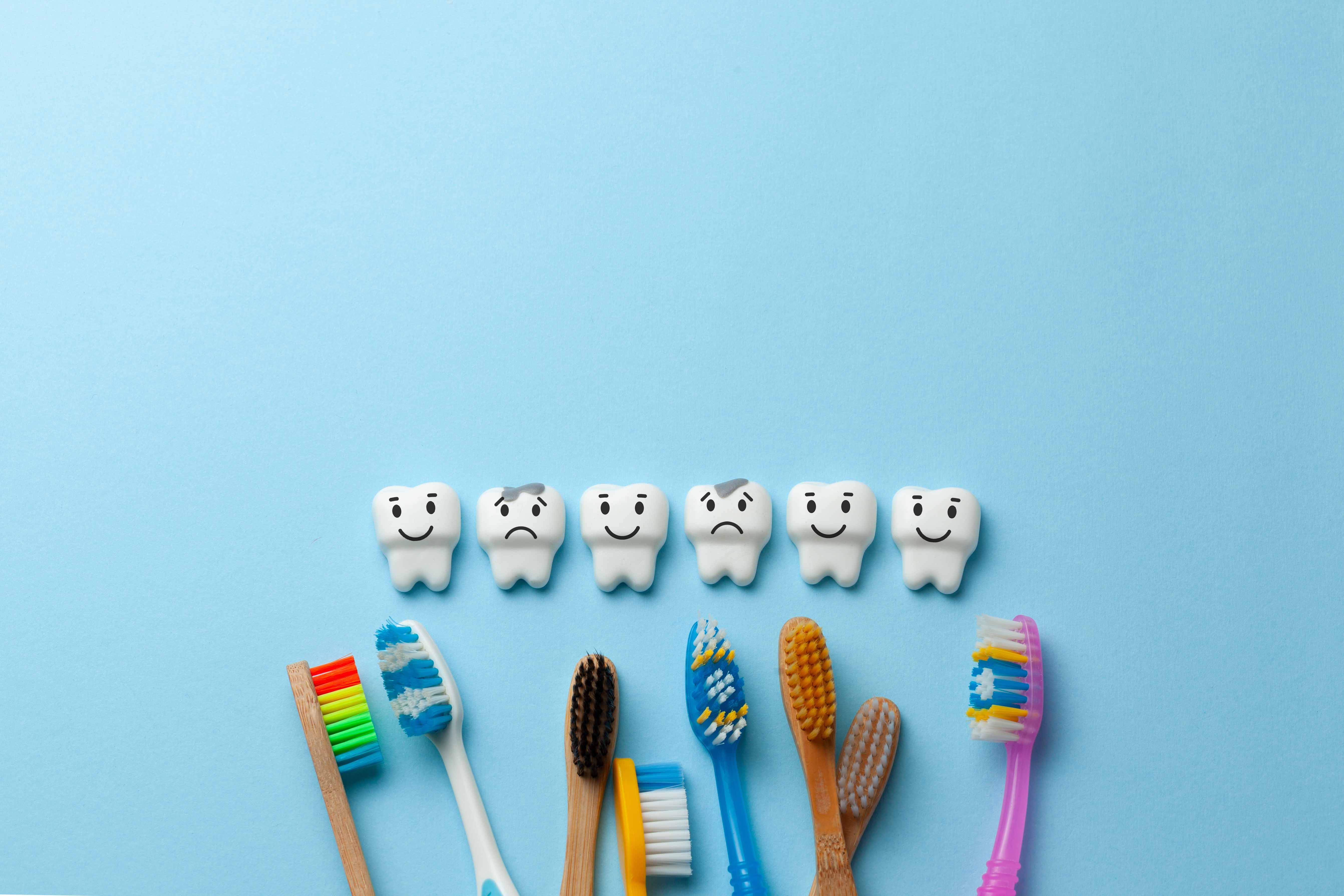 健康な歯と虫歯のキャラクターとカラフルな歯ブラシが並んでいる