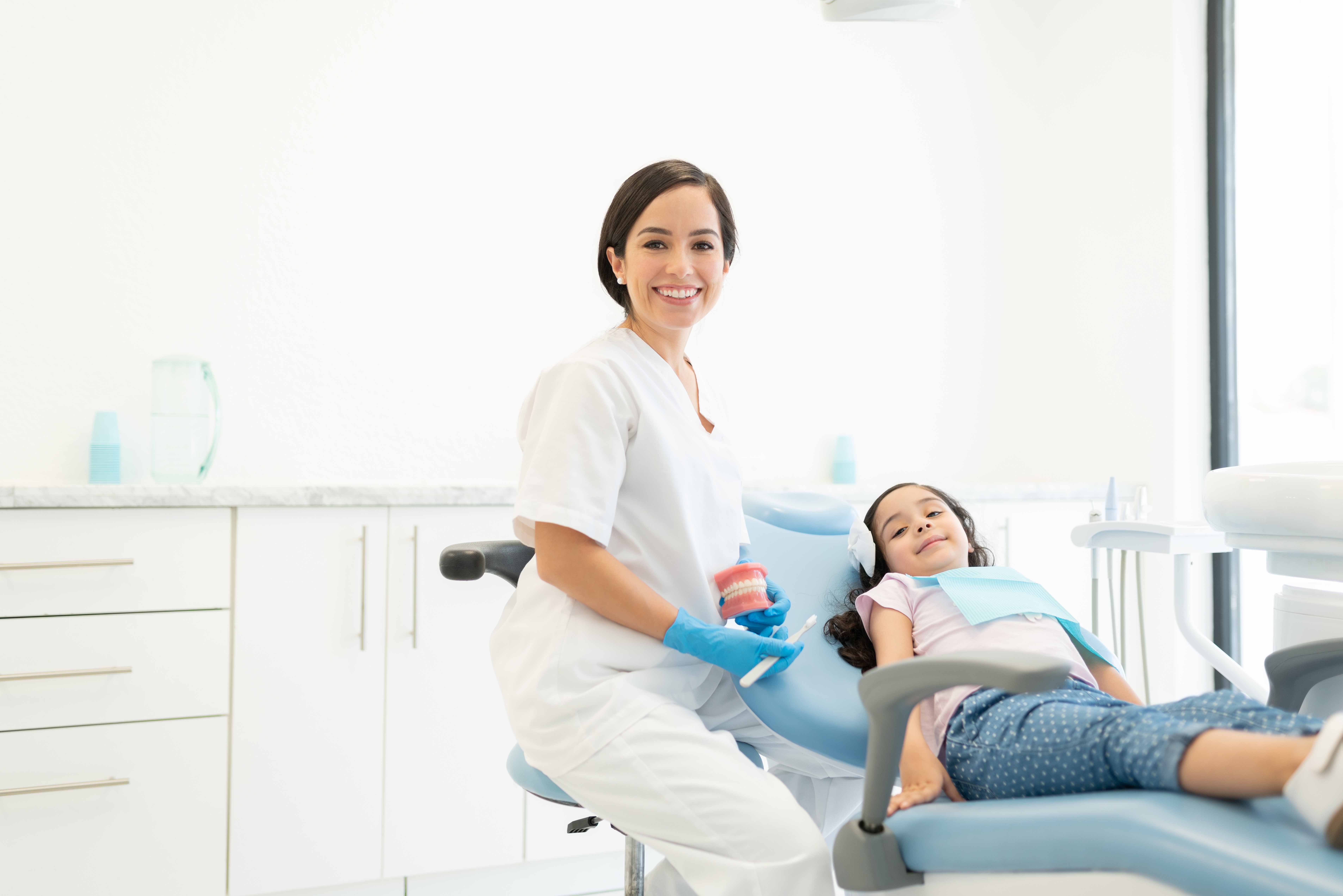 歯科医院で治療を受けている女の子と笑顔の女性歯科医師