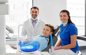 歯科の椅子に座る男の子と、その横に座る男性歯科医師・女性歯科助手