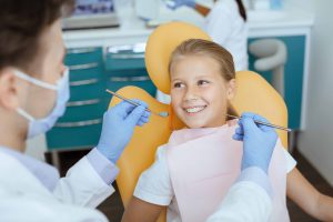 歯科医院の椅子に座り歯の治療を受ける女の子