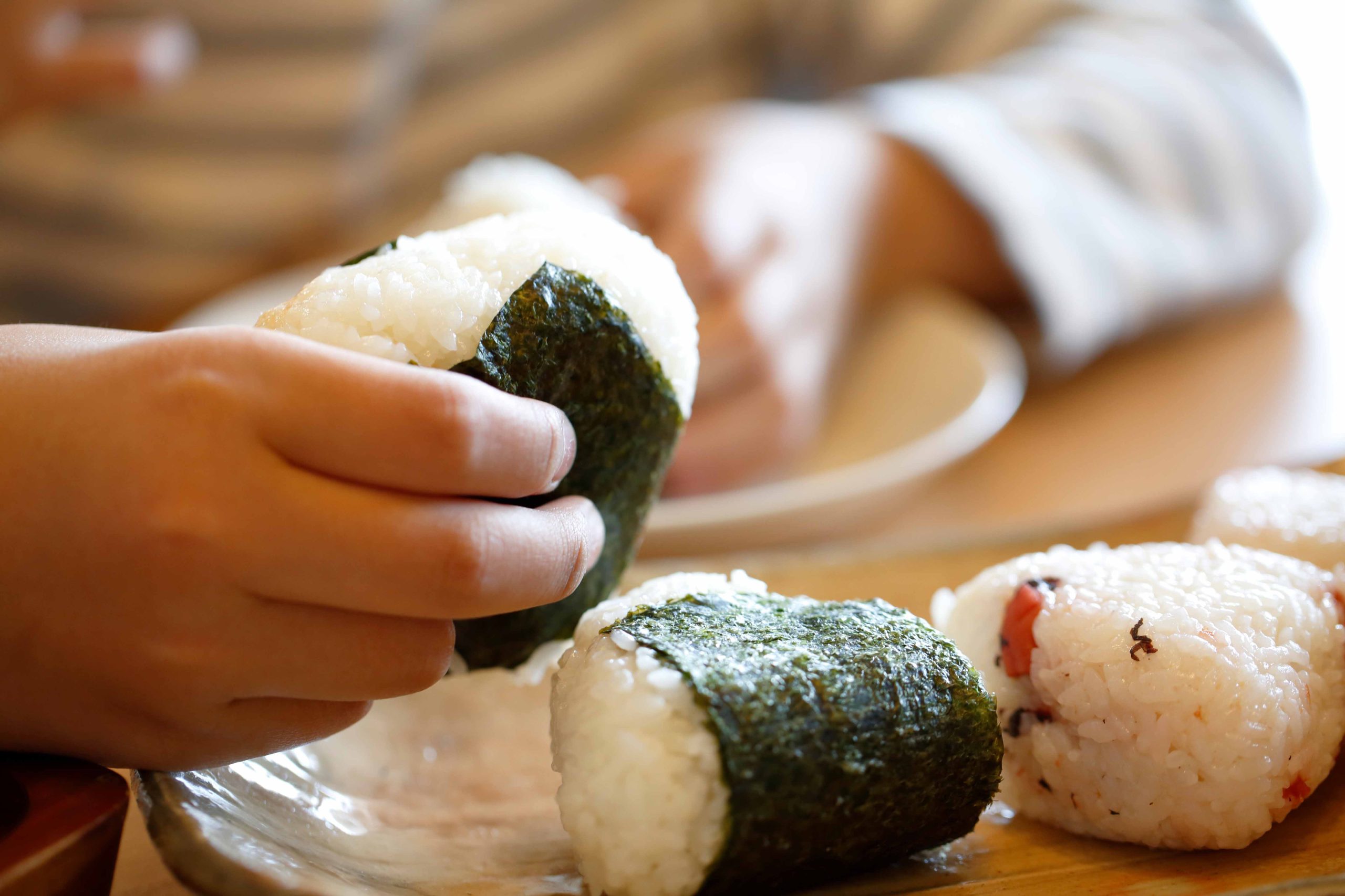 海苔巻きのおにぎりを手に持っている